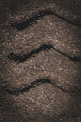 Tire tracks on the ground, creating a wavy pattern on the rocky surface