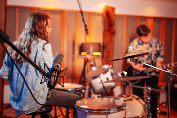 Studio microphone inside the soundproof booth with a band in a background