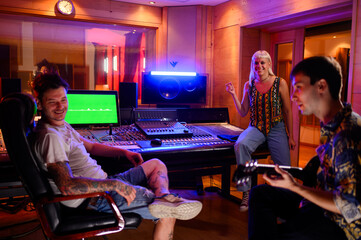 Diverse music band recording new album in a music studio with their producer