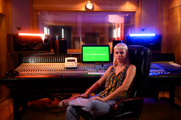 Portrait of a woman sound engineer working at mixing panel in a music studio