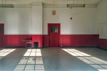 Sunlight shines through windows and onto the floor of an empty classroom in a vacant school building