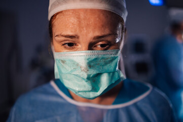 Surgeon in blue medical attire preparing for a procedure in OR