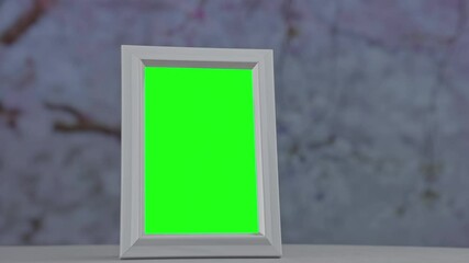 Vertical white picture frame with green screen with chroma key standing on sill with blurred garden background at winter time - Powered by Adobe