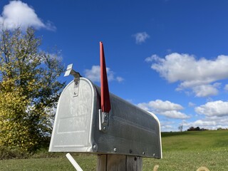 close up of a mail box on a post with blue sky and clouds in the background - gros plan d'une...