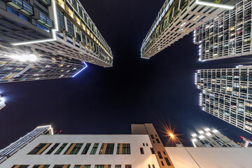 view from below into night sky of large modern skyscraper residential complex