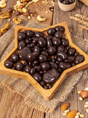 Chocolate-covered nuts on wooden background. Vertical