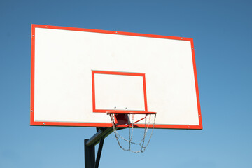 Basketball backboard hoop on sports court against clear blue sky. Outdoors. Summer game. Copy space. Mock up.