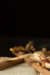 Close-up of a wooden crucifix depicting Jesus Christ with a crown of thorns, resting on an open Bible, symbolizing faith.
