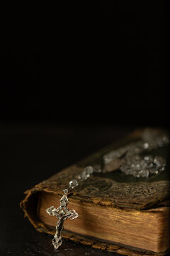 Close-up of a rosary draped over an old Bible symbolizing faith and prayer.