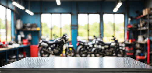 The empty stainless steel table top with blur background of Motorbike Repair Shop. For product display