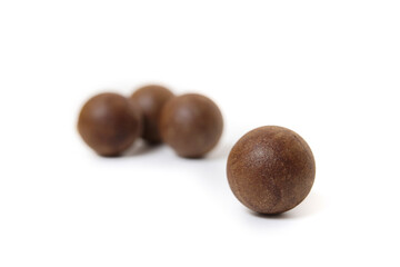 Coffee ball with defocused balls. Round brown pressed coffee balls for single use coffee maker at home. Zero waste alternative to coffee pods. Selective focus. White background.
