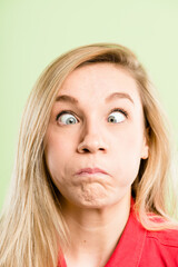 Woman, portrait and funny face with goofy expression for humor or comedy in studio on a green background. Closeup, female person or model with silly eyes for comedian character, comic or fun joke