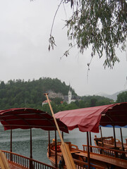 covered wood boats on a lake in Slovenia with trees and a castle in the background