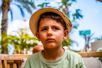chico muy joven con sombrero de paja poniendo cara triste