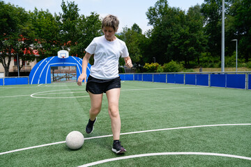 Obraz premium Mother practicing soccer moves on an outdoor field during a sunny day, focused and determined.