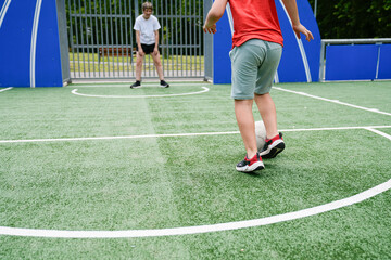 A boy in a red shirt kicks a soccer ball on a field