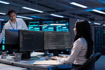 Software developer using computer, optimizing data center performance. Woman coding on PC,...