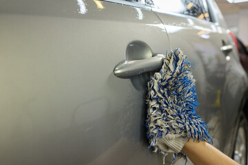 Person using blue glove for closeup car wash with brush and water