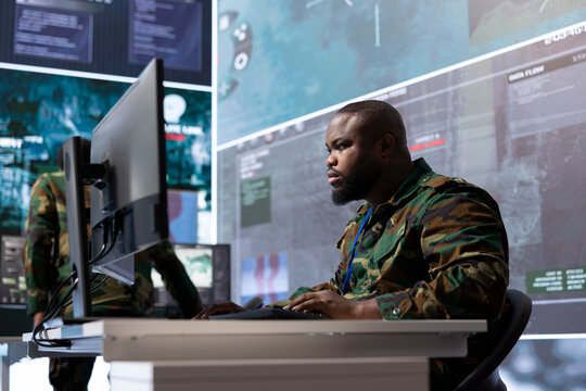 Military expert in an advanced operations center oversees satellite intelligence, managing surveillance systems on computer. Interpreting data to ensure national defense and strategic decisions.