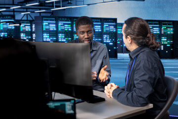 System administrators reconfiguring server room to optimize it for data processing requirements of...