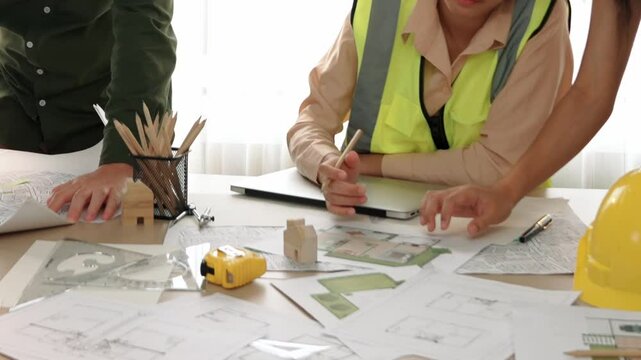 Professional engineer measuring the blueprint. Professional engineer working architectural project at studio on a table with yellow helmet and architectural equipment scatter around. Delineation.