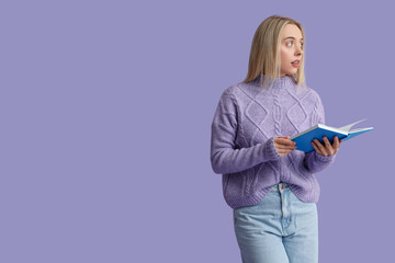 Beautiful young woman with book on lilac background