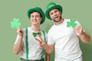 Happy young men in leprechaun's hats with clovers on green background. St. Patrick's Day celebration