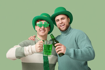 Happy young men in leprechaun's hats with beer on green background. St. Patrick's Day celebration