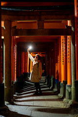 Naklejka premium Woman Taking Selfie at Night in Fushimi Inari Shrine