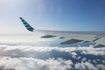 airplane wing against blue sky and white clouds
