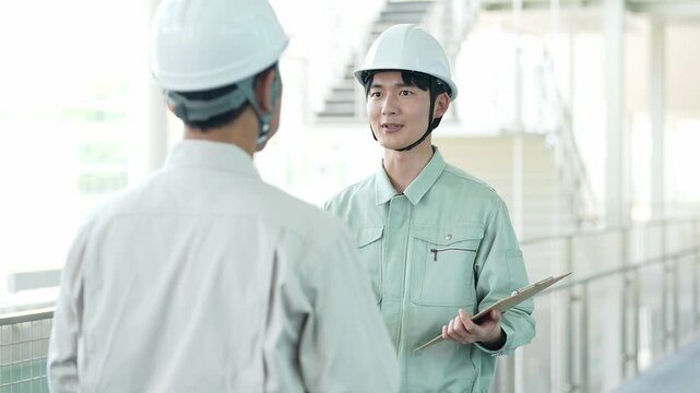 現場で打ち合わせをするヘルメットを着用した作業員