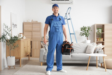 Male technician with bag of tools after repairing air conditioner in room
