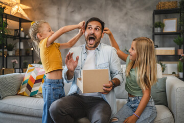 Father and daughters enjoy playful time with a surprise gift