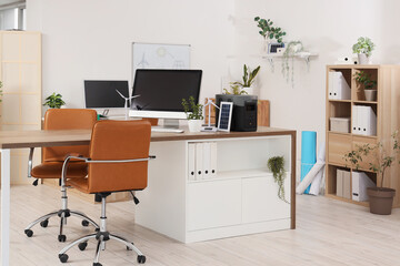 Interior of engineer's office with workplace, plants and wind turbine models