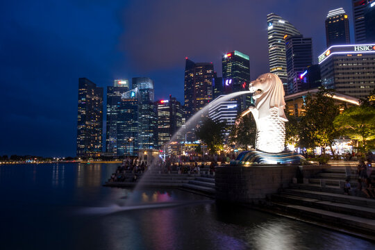 Merlion statue fountain in Merlion Park and Singapore city skyline at night