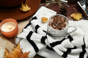 Autumn composition with cup of cocoa, candle and sweater on plaid as background