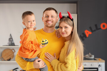 Happy parents and their little son with Halloween pumpkin in kitchen