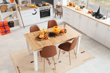 Interior of kitchen decorated for Halloween with dining table and pumpkins