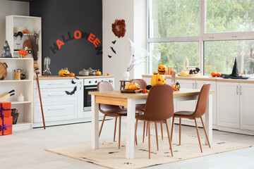 Interior of kitchen decorated for Halloween with dining table and pumpkins