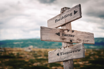 building better tomorrow text quote on wooden directional signpost outdoors in nature