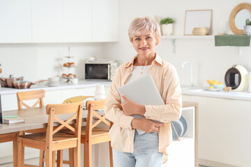 Mature woman with laptop in kitchen