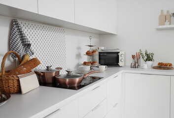 Cooking pot with frying pan on stove in light kitchen