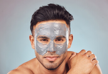 Skincare, portrait and man with mask, charcoal face treatment and product for skin glow on blue background. Cosmetics, dermatology and male person with clay facial detox for morning routine in studio