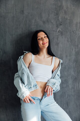 Fashion Brunette Woman In Jeans And Jacket Near Gray Wall Model Posing