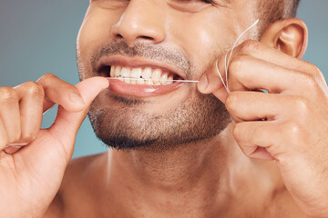 Studio, mouth and man with floss for dental, gum health and wellness with cleaning for fresh breath. Male model, product and string by gray background for teeth care, gingivitis and oral hygiene