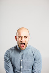 Shouting, screaming and portrait of angry man in studio with anger, upset and crazy reaction. Body language, facial expression and isolated person with loud noise, voice and comic on gray background