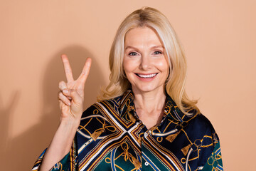 Portrait of blonde hair happy mature business lady in glamour shirt showing v sign gesture hello...