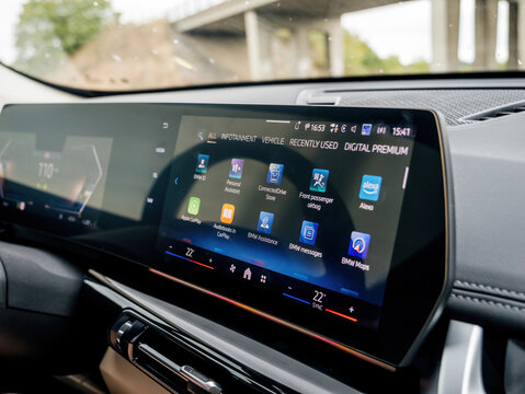 Munich, Germany - Sep 8, 2024: The curved display of a BMW iX1 electric car shows all the applications while driving under a bridge, emphasizing the vehicle's advanced dashboard technology