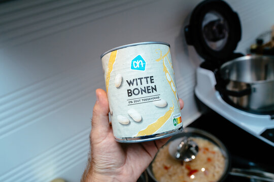 Haarlem, Netherlands - Sep 1, 2024: A POV shot of a male hand holding an Albert Heijn beans can labeled Witte Bonen, translated as White Beans, showcasing the product in focus.