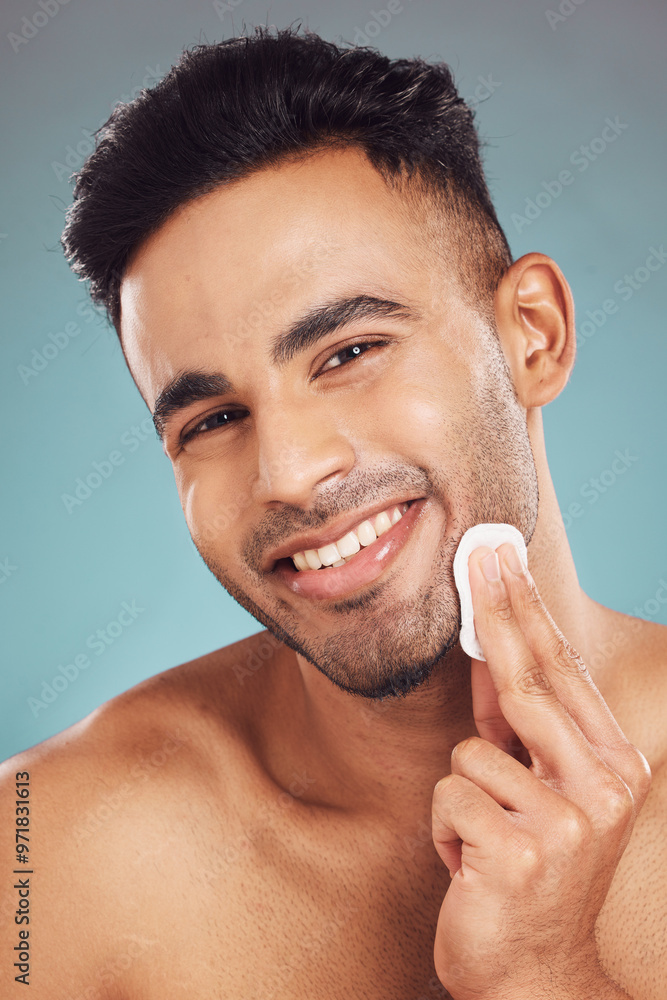 Poster Man, cotton pad and studio portrait for skincare with hygiene, cleaning and grooming by blue background. Person, model and beard with smile for dermatology, wellness and cosmetics for transformation